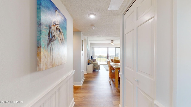 corridor featuring a textured ceiling and light hardwood / wood-style flooring