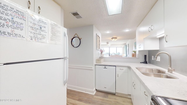 kitchen featuring light wood-type flooring, white appliances, white cabinetry, sink, and a textured ceiling