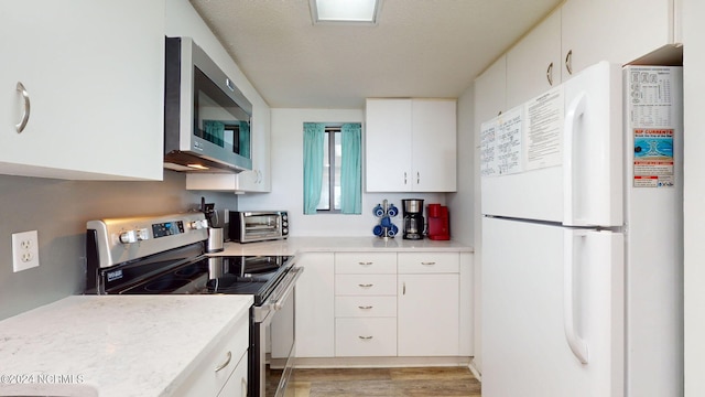 kitchen featuring appliances with stainless steel finishes, light hardwood / wood-style flooring, and white cabinets