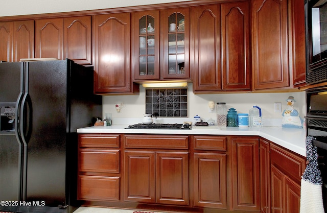 kitchen with black refrigerator with ice dispenser and stainless steel gas stovetop