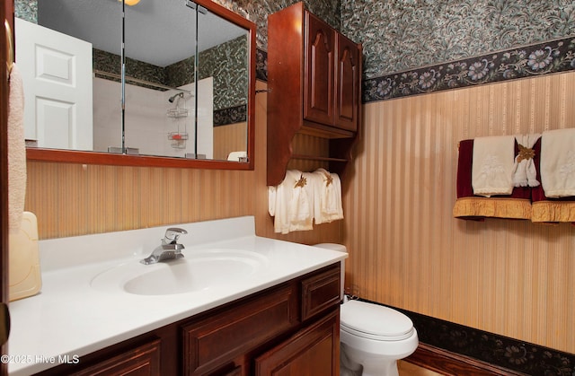 bathroom featuring toilet, a textured ceiling, and vanity