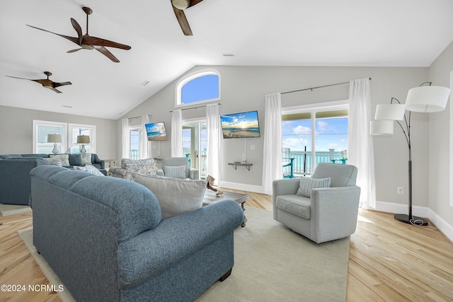 living room featuring lofted ceiling, light wood-style floors, plenty of natural light, and baseboards