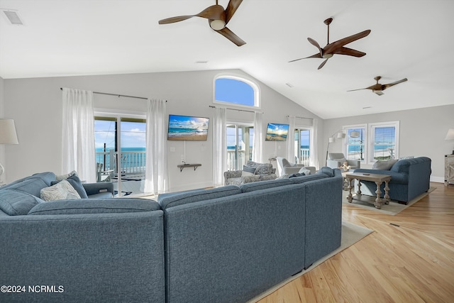 living area with lofted ceiling, a wealth of natural light, wood finished floors, and visible vents