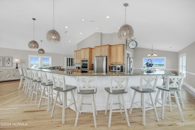 kitchen with appliances with stainless steel finishes, dark stone counters, and a large island with sink