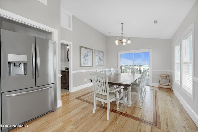 dining room with lofted ceiling, plenty of natural light, light wood-style flooring, and a notable chandelier