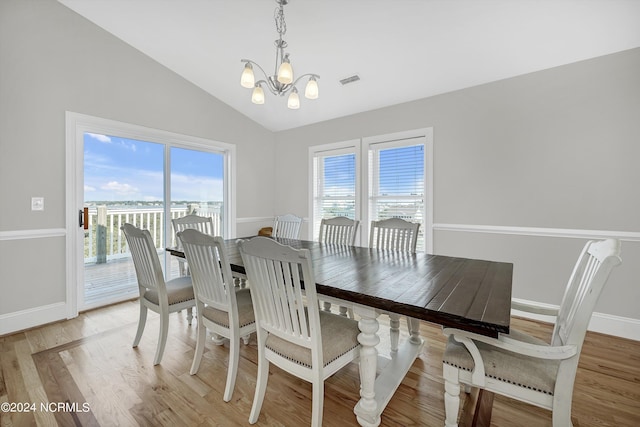 dining space with a notable chandelier, visible vents, light wood-style floors, vaulted ceiling, and baseboards