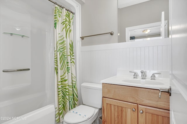 full bath with a wainscoted wall, shower / bath combination with curtain, vanity, and toilet