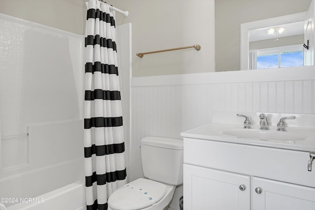 bathroom featuring a wainscoted wall, vanity, toilet, and shower / bathtub combination with curtain