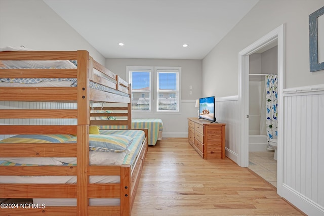 bedroom featuring recessed lighting, a wainscoted wall, light wood-style flooring, and ensuite bath