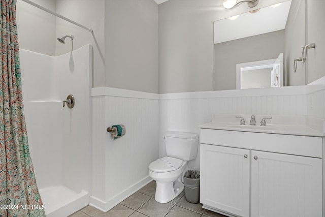 bathroom featuring a stall shower, wainscoting, toilet, tile patterned floors, and vanity