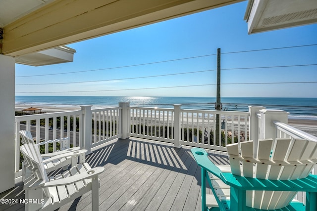 wooden terrace featuring a water view and a beach view