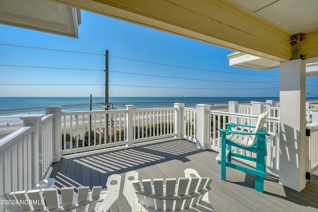 wooden terrace featuring a water view and a beach view