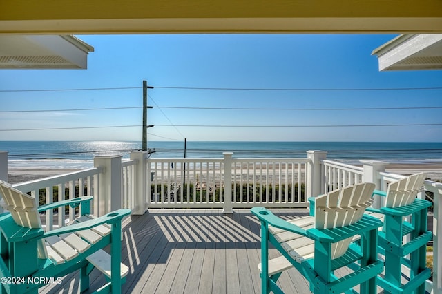 wooden deck with a water view and a beach view