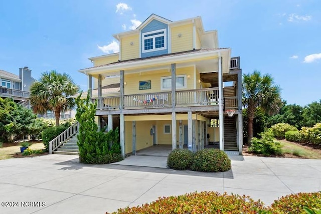 coastal inspired home featuring a carport, a porch, stairway, and driveway