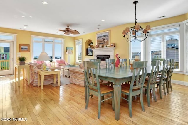 dining area featuring light wood-type flooring and ceiling fan with notable chandelier