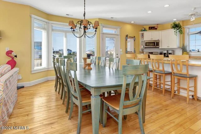 dining area with ceiling fan with notable chandelier and light wood-type flooring