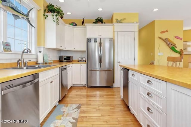 kitchen featuring white cabinets, stainless steel appliances, light hardwood / wood-style floors, and sink