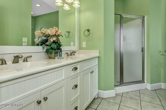 bathroom with double vanity, a shower stall, a sink, and tile patterned floors