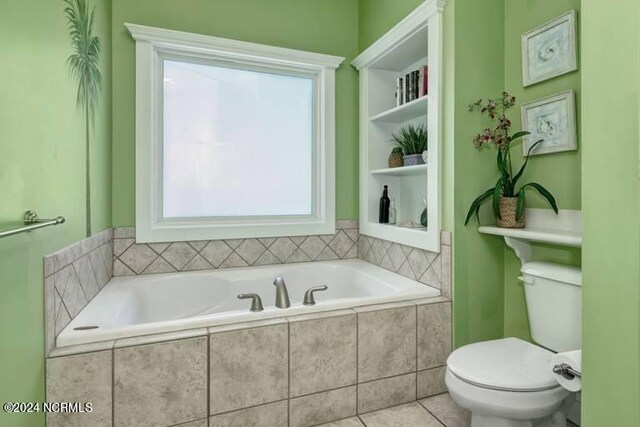 bathroom with toilet, tiled tub, and tile patterned floors