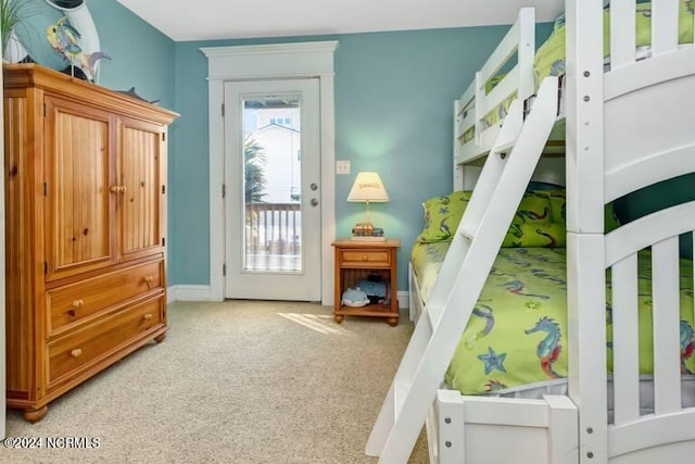 bedroom with access to exterior, light carpet, and baseboards