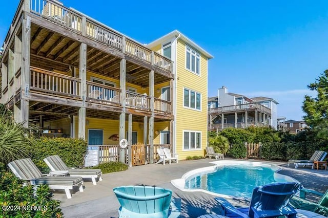 rear view of house with a balcony, a fenced in pool, and a patio area