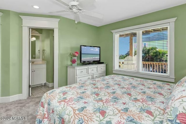 bedroom with a ceiling fan, light carpet, connected bathroom, and baseboards