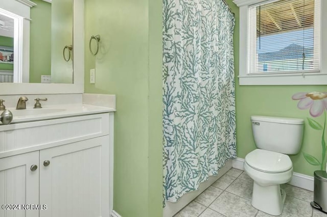 bathroom featuring toilet, vanity, a shower with curtain, baseboards, and tile patterned floors