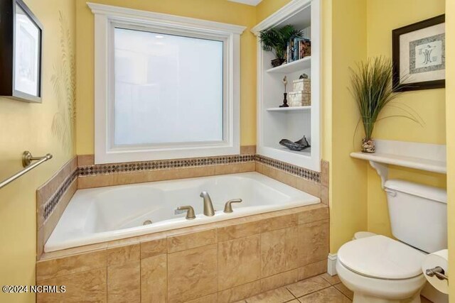 bathroom with toilet, tiled tub, and tile patterned floors