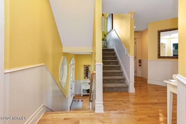 staircase featuring wainscoting and wood finished floors