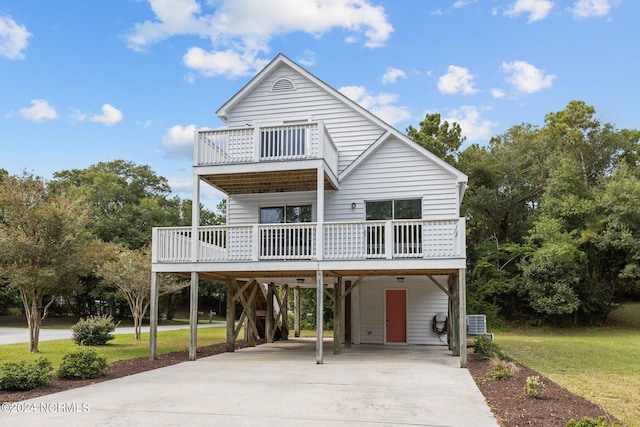 coastal home featuring a carport, a balcony, central air condition unit, and a front lawn