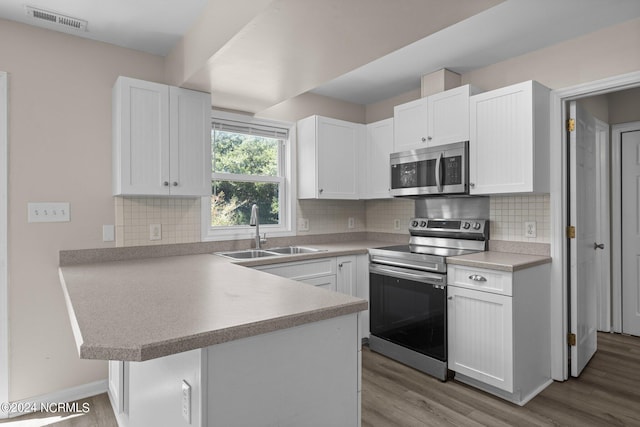 kitchen featuring kitchen peninsula, white cabinets, stainless steel appliances, and light hardwood / wood-style floors