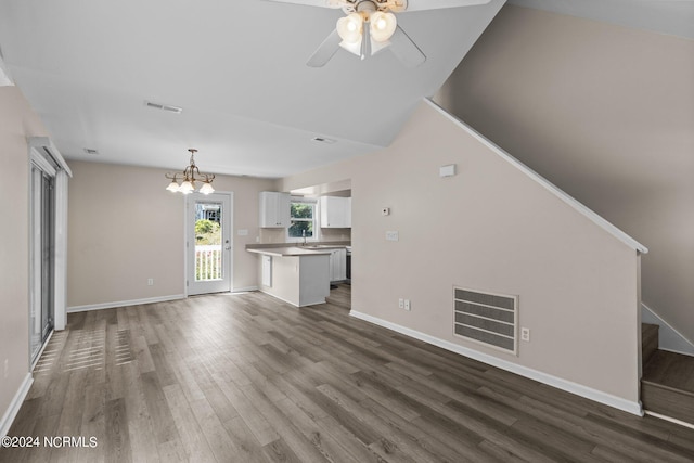 unfurnished living room with hardwood / wood-style floors, ceiling fan with notable chandelier, and lofted ceiling