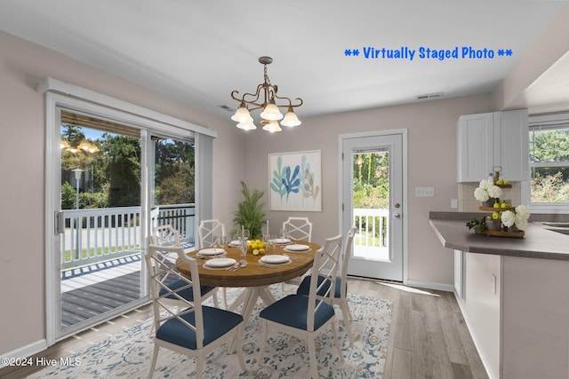 dining space with light hardwood / wood-style floors and an inviting chandelier