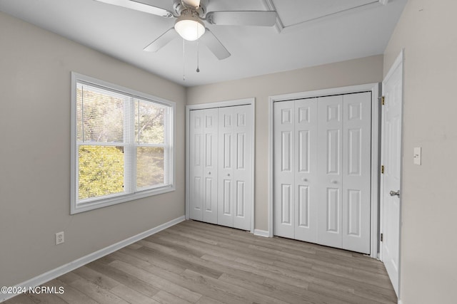 unfurnished bedroom featuring ceiling fan, light hardwood / wood-style flooring, and two closets