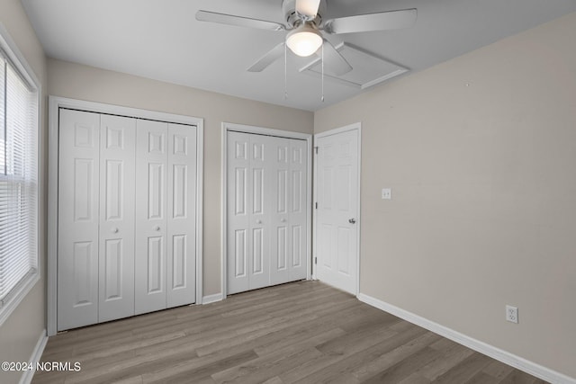 unfurnished bedroom featuring two closets, light hardwood / wood-style flooring, and ceiling fan