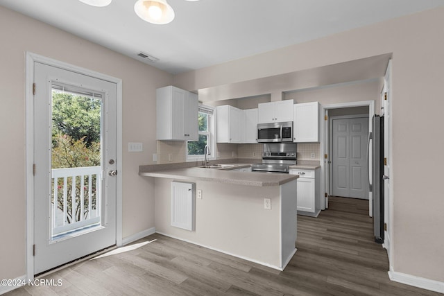 kitchen with white cabinets, backsplash, kitchen peninsula, and stainless steel appliances