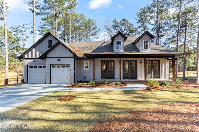 view of front of home featuring french doors, a front yard, a porch, and a garage