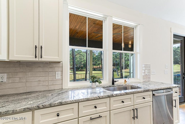 kitchen with sink, stainless steel dishwasher, light stone countertops, tasteful backsplash, and white cabinetry