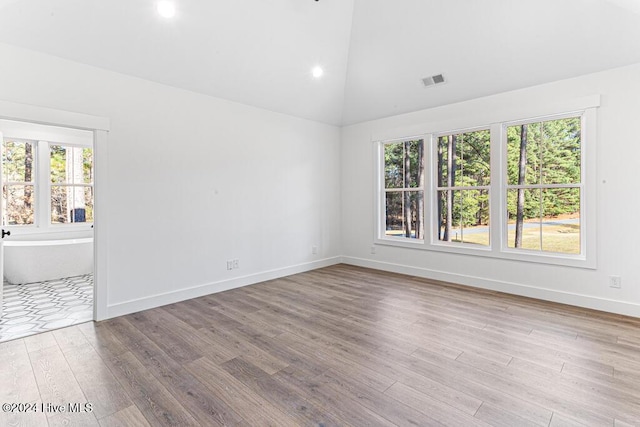 empty room with high vaulted ceiling and light hardwood / wood-style flooring