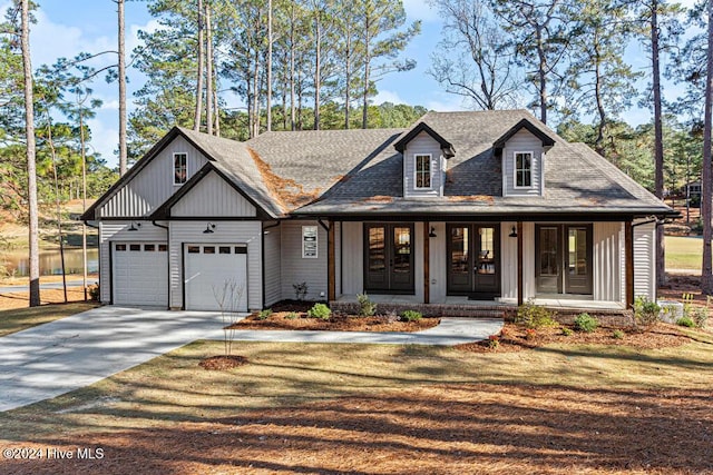 view of front of house with covered porch, french doors, a garage, and a front yard