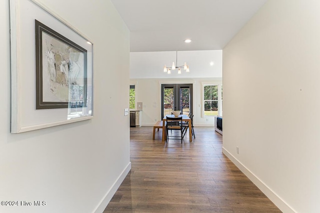 hall featuring dark hardwood / wood-style flooring, french doors, and an inviting chandelier