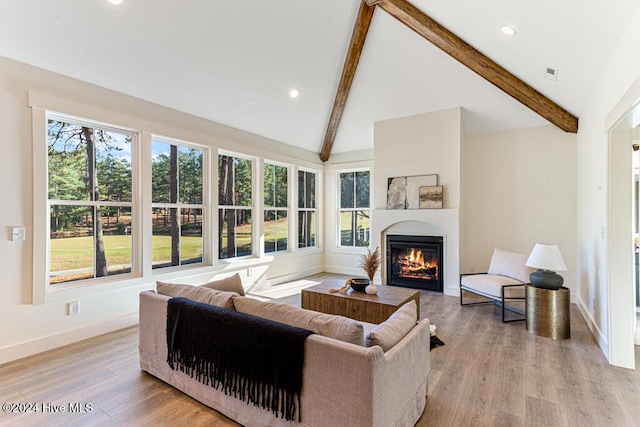 living room featuring beam ceiling, high vaulted ceiling, a healthy amount of sunlight, and light hardwood / wood-style floors