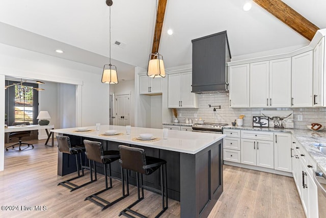 kitchen with white cabinets, custom range hood, light hardwood / wood-style flooring, and a kitchen island