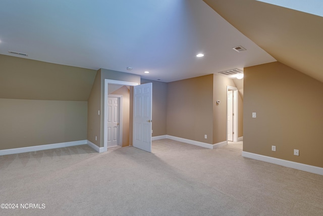 additional living space featuring vaulted ceiling and light carpet