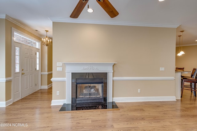 living room with ceiling fan with notable chandelier, crown molding, and light hardwood / wood-style flooring