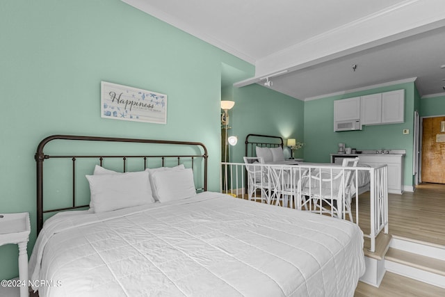 bedroom featuring crown molding, baseboards, and wood finished floors