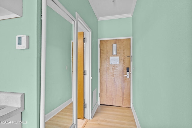 hallway with ornamental molding, baseboards, and light wood finished floors