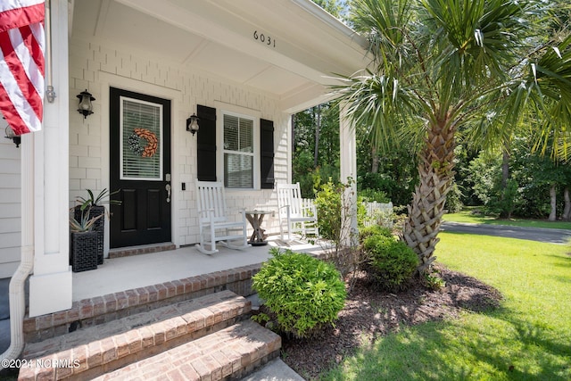 property entrance featuring a lawn and a porch