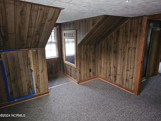 bonus room with lofted ceiling, wood walls, and carpet