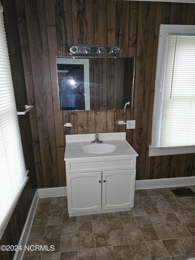 bathroom featuring visible vents, wood walls, vanity, and baseboards